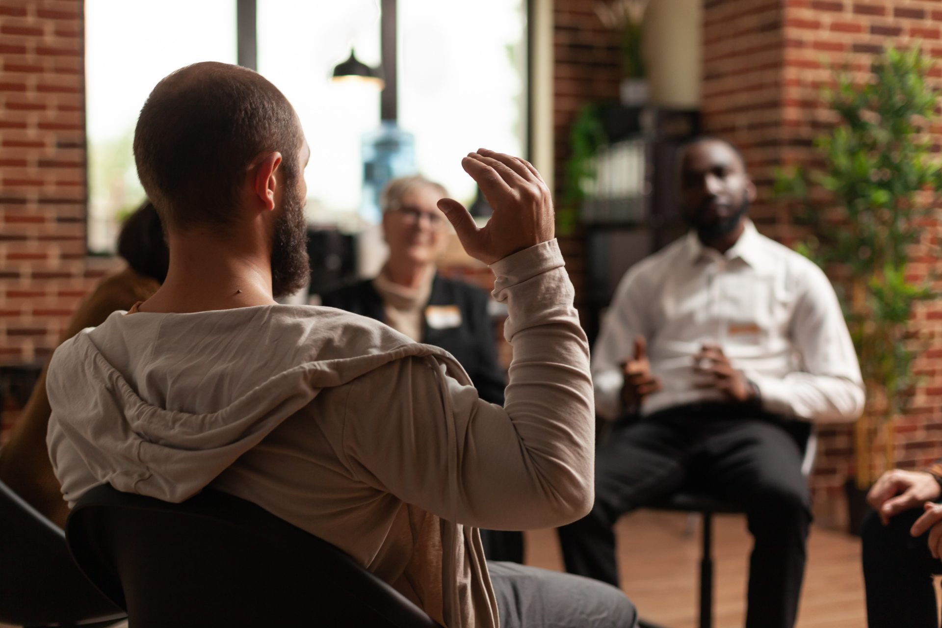 Group discussion in a community service or alcohol education class, with a focus on a participant raising their hand to speak, emphasizing engagement in DUI-related education.